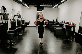 owner standing in the middle of her salon, with chairs and hair washing stations on each side