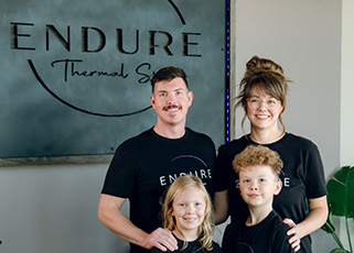 Katie and Ethan Pendley and 2 kids in front of their business sign