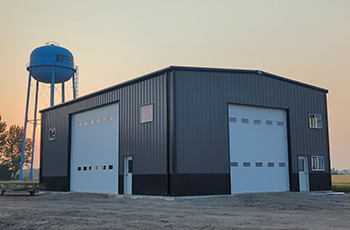 photo of in the evening with water tower on the left back of the shop building with 2 garage doors on 2 sides