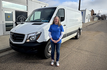 Owner, Rhonda, standing in front of the business white van