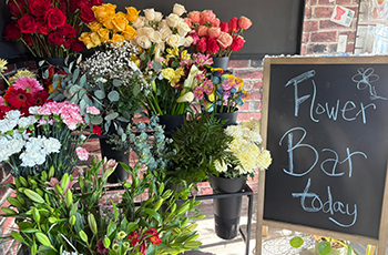 chalk board sign with name written in it with flower vases surrounding it
